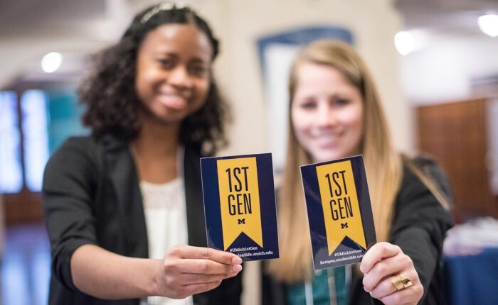 Two students holding up FirstGen stickers